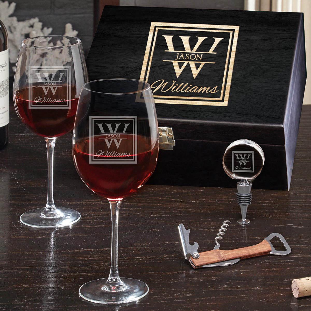 a table with a custom black wooden box, 2 custom wine glasses, a wine bottle opener, and custom wine stopper