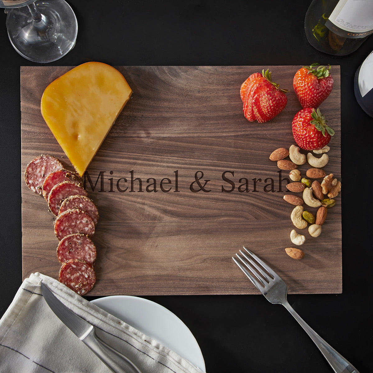 customized wooden walnut cutting board with nuts, cheese, meats, and fruit slices